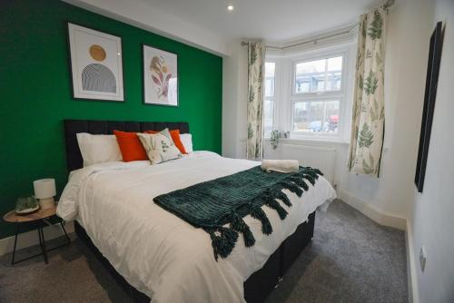 a green bedroom with a bed and a green wall at The Tenstay -Comfortable 5BR Home Close To All in Ifield
