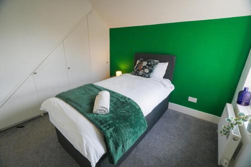 ein grün-weißes Schlafzimmer mit einem Bett mit einer grünen Wand in der Unterkunft The Tenstay -Luxury 5BR Home Close To All in Ifield
