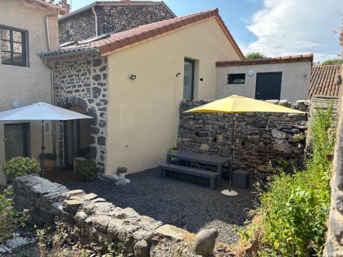 un patio avec un parasol et un banc et un bâtiment dans l'établissement En si bon chemin - Gîte chemin 430, à Le Monastier sur Gazeille