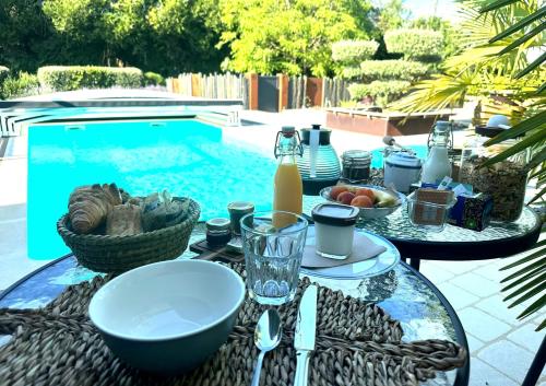 a table with plates of food on it next to a swimming pool at A la Jolie Campagne - chambre et table d'hôtes in Lorigné