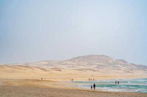 a group of people on a beach in the desert at Occidental Boa Vista Beach in Rabil