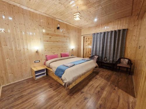 a bedroom with a bed and a wooden wall at Hotel Kaza Manjushree in Kaza