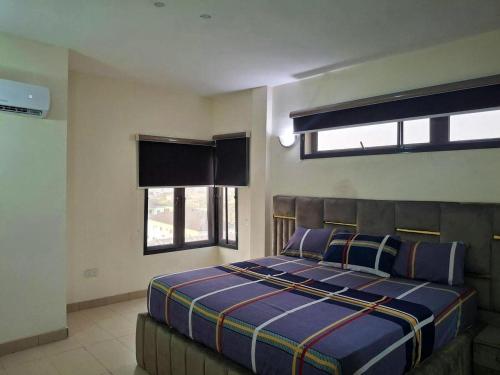a bedroom with a bed and two windows at Lagos Luxury Residence Opebi in Ikeja