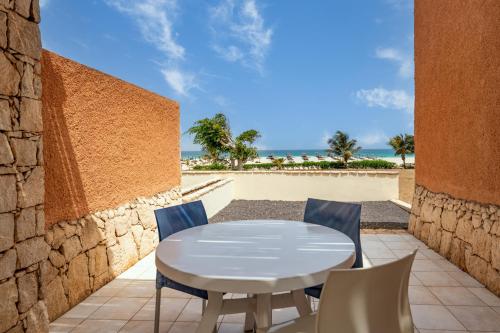 a white table and chairs on a patio with the beach at Occidental Boa Vista Beach in Rabil