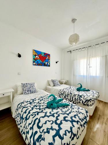 a bedroom with two beds with blue and white sheets at Pirata Milfontes Guest House in Vila Nova de Milfontes