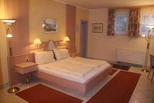 um quarto com uma grande cama branca e 2 candeeiros em Waldschlössl em Latschach ober dem Faakersee