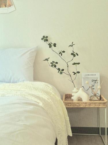 a bedroom with a bed and a branch on a table at Eumm stay in Cheongju