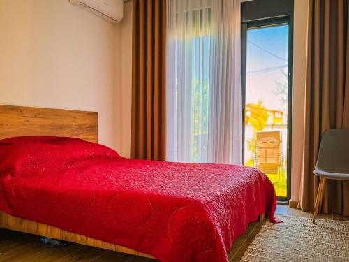 a bedroom with a red bed and a large window at TaNa's Apartments in Donji Štoj