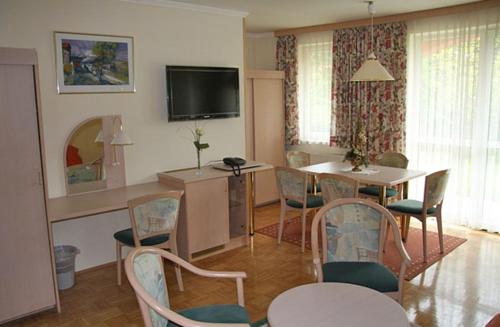 a living room with a table and chairs and a television at Waldschlössl in Latschach ober dem Faakersee