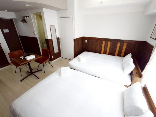 a bedroom with two beds and a table and a chair at N's Hotel 平和公園 in Hiroshima