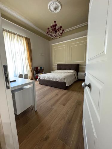 a bedroom with a bed and a desk and a chandelier at Le suite del Duomo - 2 in Cava deʼ Tirreni