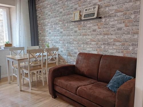 ein Wohnzimmer mit einer Couch und einer Ziegelwand in der Unterkunft Les meublés de Louis-Marie, 2 appartements indépendants pour 4 personnes, 8 personnes au total, proche du Puy du Fou in Saint-Amand-sur-Sèvre