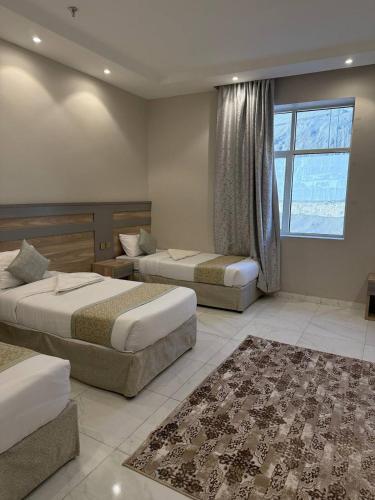 a bedroom with two beds and a window and a rug at فندق الروابط للضيافة السياحي مكة in Makkah