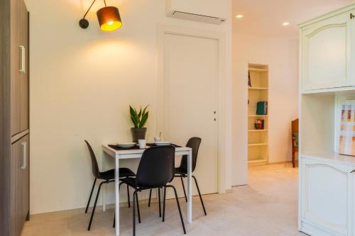 a dining room with a white table and black chairs at Magnolia house- monolocale con ingresso indipendente in Civitanova Marche
