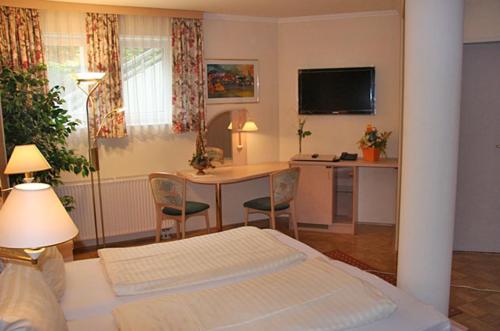 a bedroom with a bed and a table and a kitchen at Waldschlössl in Latschach ober dem Faakersee