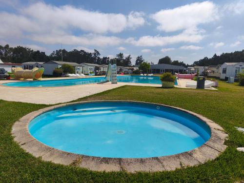 a large blue pool in a yard with houses at Casa de Camping Land's Hause in Pataias
