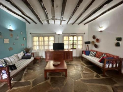 a living room with couches and a piano at Rafiki Villa in Mombasa