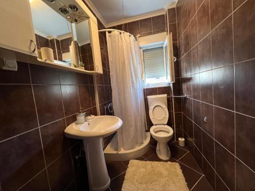 a bathroom with a sink and a toilet and a mirror at Galeb in Igalo