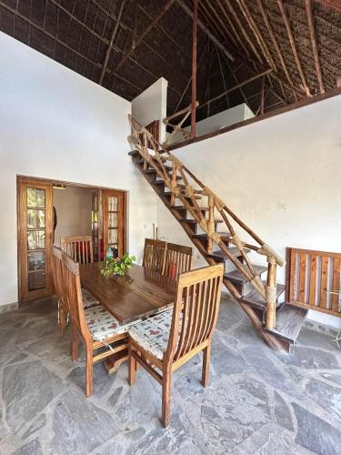 a dining room with a wooden table and a staircase at Rafiki Villa in Mombasa