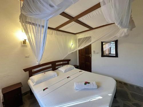 a bedroom with two beds with white drapes at Rafiki Villa in Mombasa