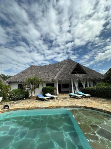 a house with a large swimming pool in front of it at Rafiki Villa in Mombasa
