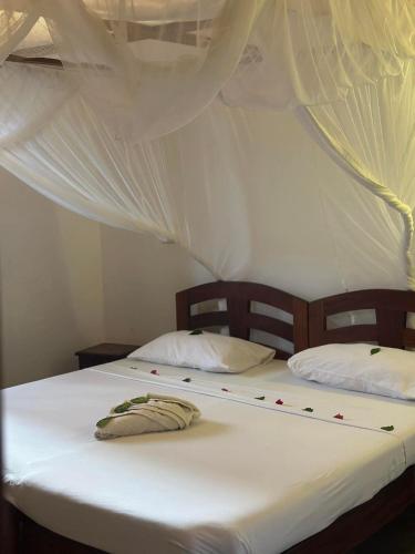 two beds in a room with white curtains at Rafiki Villa in Mombasa