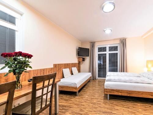 a bedroom with two beds and a table and a couch at Apartmány Vila Hedvika in Rožnov pod Radhoštěm