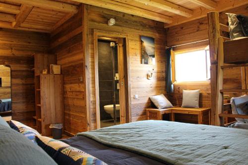 a bedroom with a bed in a wooden cabin at Chambres et Tables d'Hôtes Le Choton à Nono - Col du Joly Beaufortain in Hauteluce