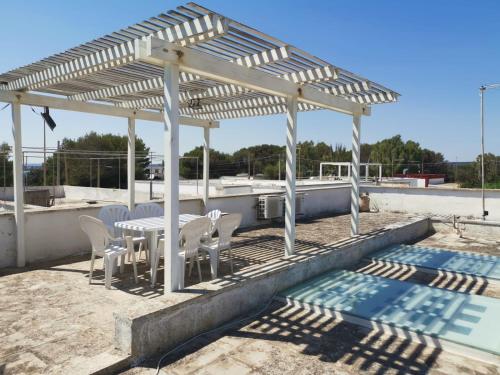 a white pergola with a table and chairs next to a pool at Villa Lucky in Punta Prosciutto
