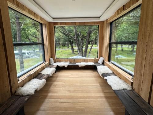 a room with benches and windows in a forest at Refugio de Glaciares in El Chalten