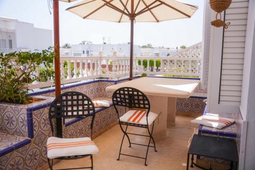 a balcony with a table and chairs and an umbrella at Dar Ullaya in Hammamet