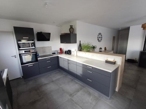 a kitchen with blue cabinets and a white counter top at Au cœur des pierres dorées in Bully