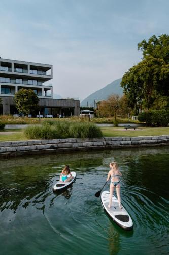 two girls are on paddle boards in the water at Swiss Diamond Boutique Hotel - La Romantica in Melide