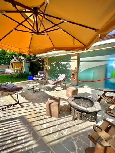 a patio with furniture and a large yellow umbrella at Luxury Villa in Yerevan in Yerevan