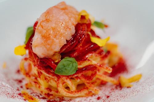 a plate of food with shrimp on top of pasta at Swiss Diamond Boutique Hotel - La Romantica in Melide