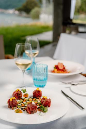 a table with two plates of food and glasses of wine at Swiss Diamond Boutique Hotel - La Romantica in Melide