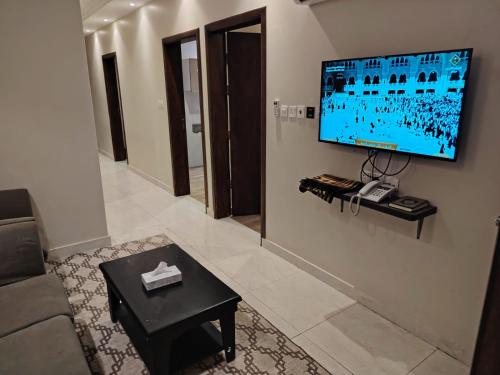 ein Wohnzimmer mit einem Sofa und einem Fernseher an der Wand in der Unterkunft خزامى للشقق المخدومة in Sufan