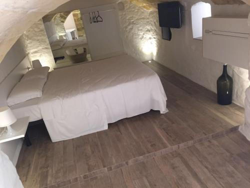 a bedroom with a white bed and a wooden floor at La casa del nonno in Matera