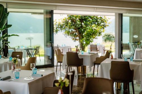 a restaurant with white tables and chairs and a tree at Swiss Diamond Boutique Hotel - La Romantica in Melide