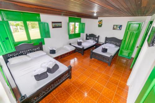 a room with two beds and green shuttered windows at Finca Hotel el Rocio in Circasia