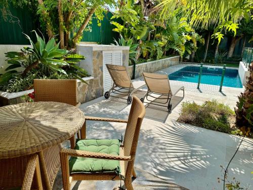 un patio avec une table et des chaises et une piscine dans l'établissement Charming cottage, pool & garden by Guincho beach, à Aldeia de Juso