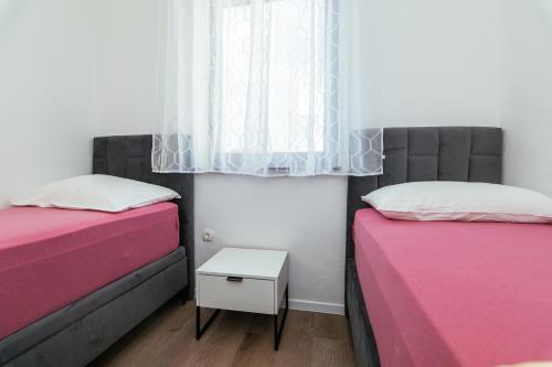 two beds in a small room with a window at Pansion Čirjak in Sveti Filip i Jakov