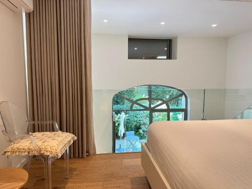 une chambre avec un lit, une chaise et une fenêtre dans l'établissement La Verrière du Palais - Triplex contemporain avec jardin, à Avignon