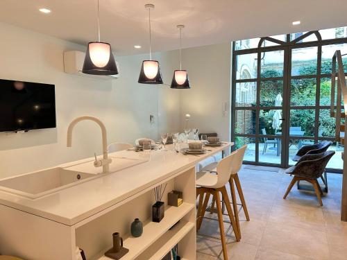 une cuisine avec un évier et un bar avec des chaises dans l'établissement La Verrière du Palais - Triplex contemporain avec jardin, à Avignon