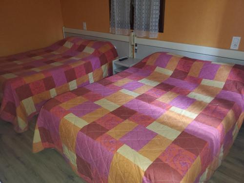 two beds in a room with a colorful quilt at Hotel des Voyageurs in Millau