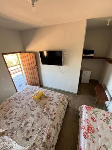 a bedroom with two beds and a tv on the wall at Quintal De Minas in Delfinópolis