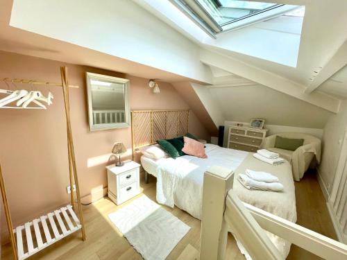 une chambre mansardée avec deux lits et une lucarne dans l'établissement Le Petit Cote Ouest - appt dans les Pins près de la plage, à Les Sables-dʼOlonne