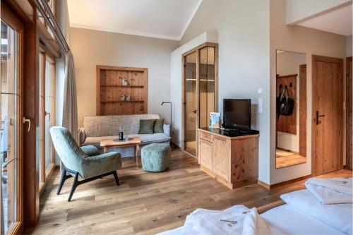 a room with a bed and a couch and a tv at Sonnenhof Genusshotel & Appartements in Pertisau