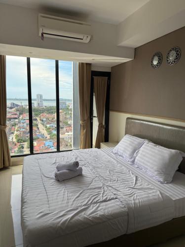 a bed with a towel on it in a room with windows at Pollux Habibie Deluxe Sea View By Superstay in Batam Center