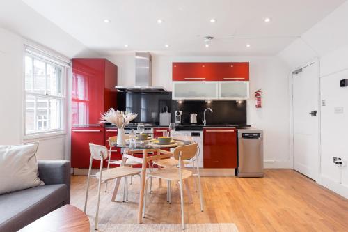 a kitchen with a table and a kitchen with red cabinets at Bright Carnaby Soho 1BR Apartment with AC in London